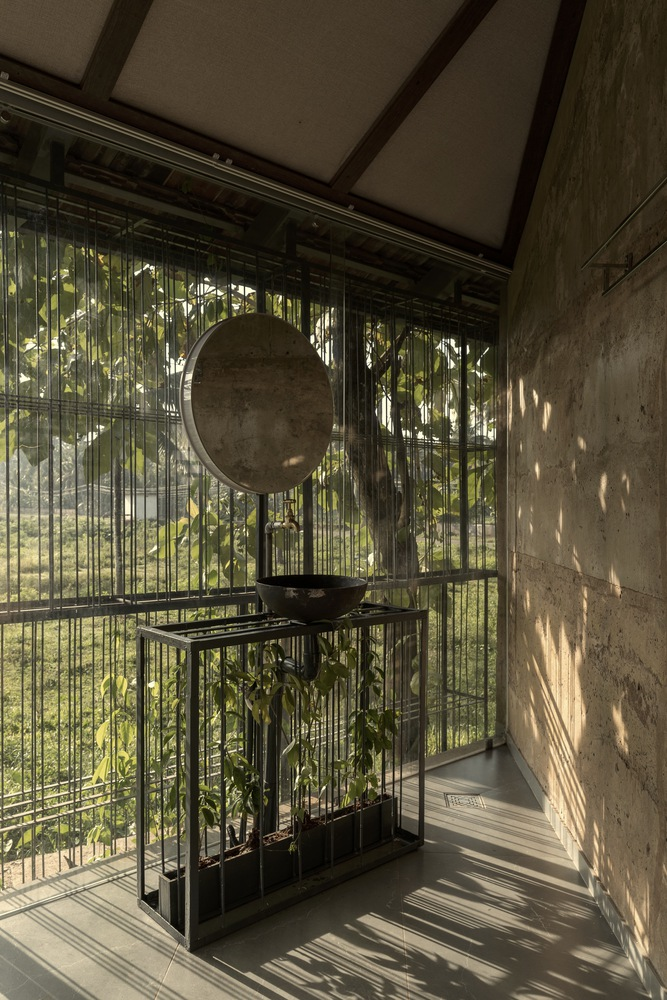 Bathroom with circular mirror and wire mesh balustrade filtering dappled light from the trees outside
