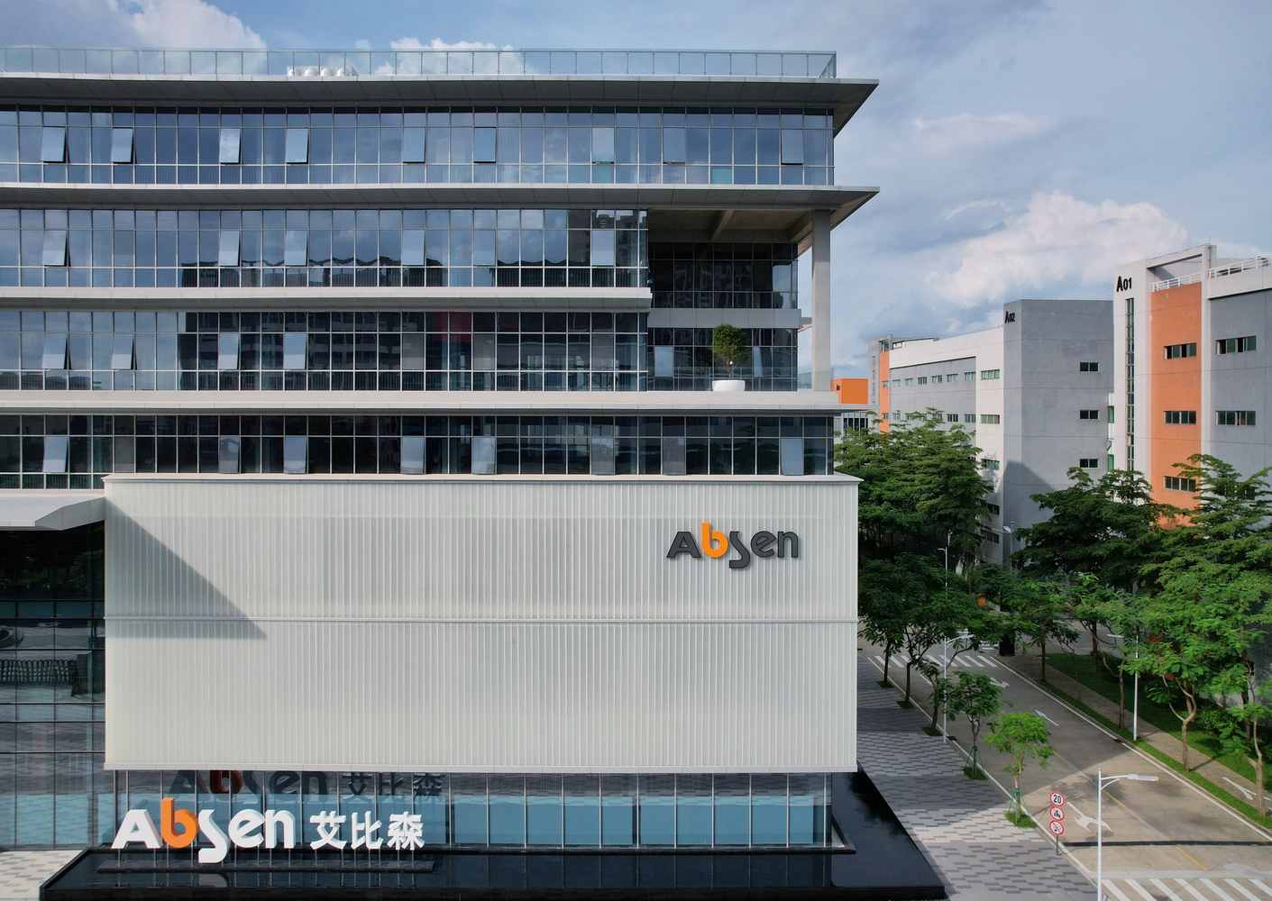 Exterior view of the horizontal facade with vertical sun screens and street-level trees in afternoon light