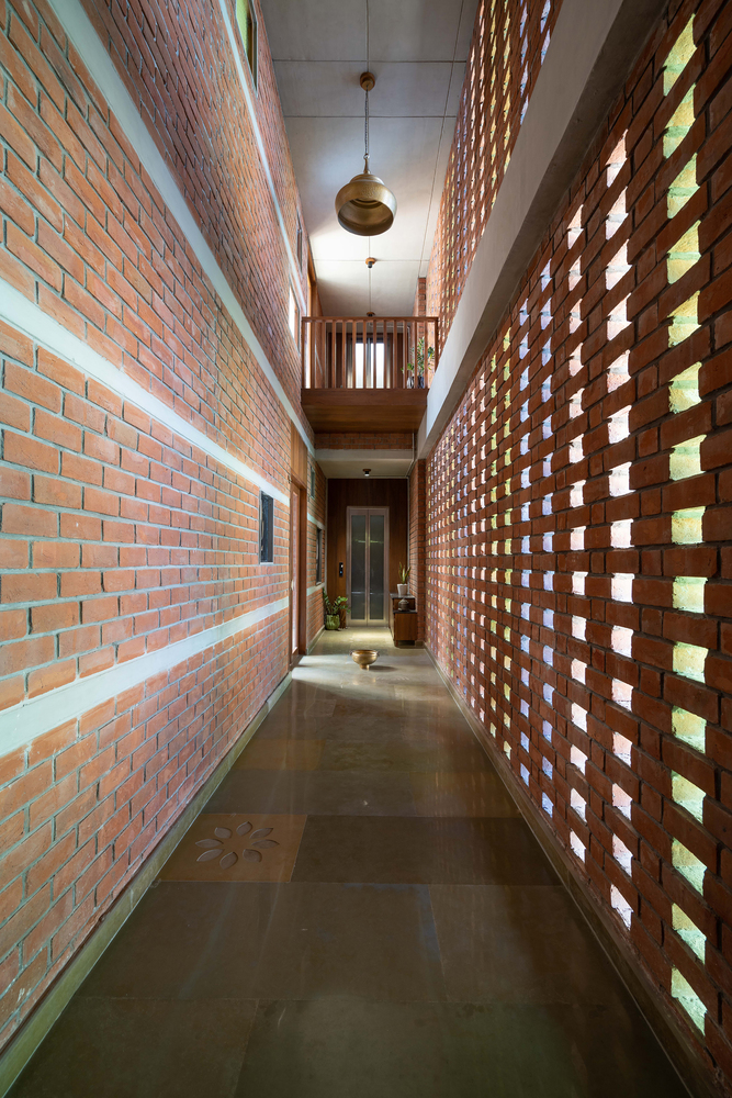 Corridor flanked by perforated brick screen wall with glass block openings filtering daylight through