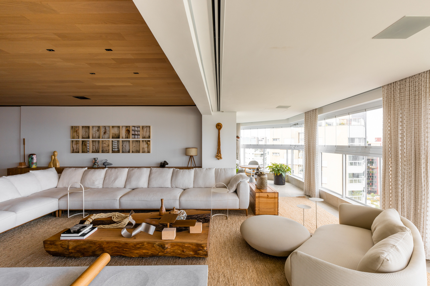 Seating area beneath intersecting timber and white ceiling planes with city views beyond