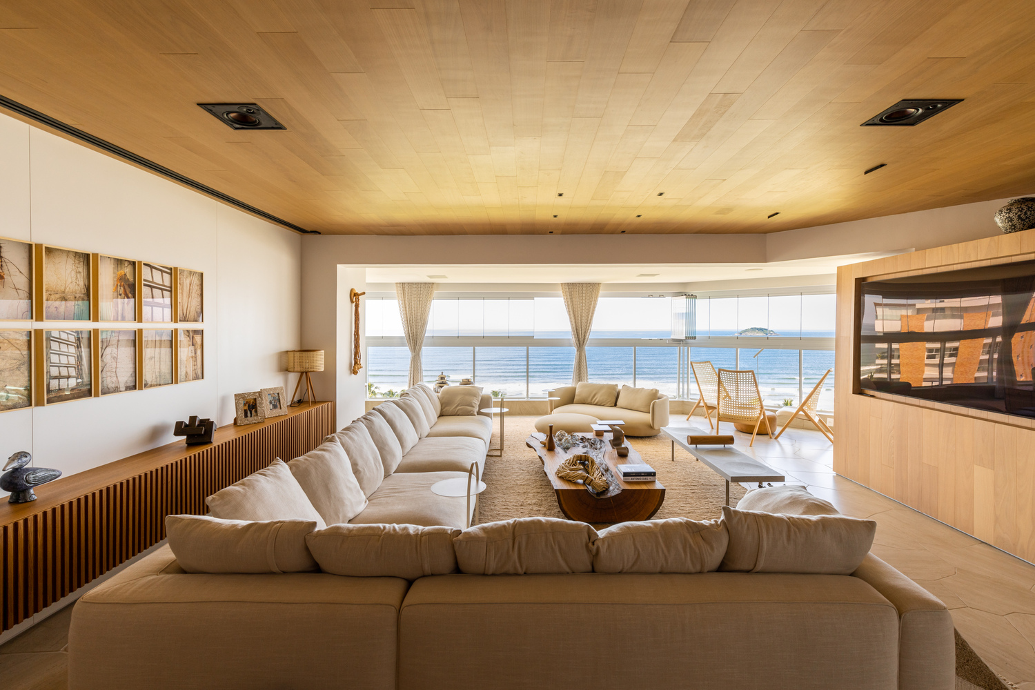 Living space with ribbed timber ceiling and panoramic seaside views through continuous glazing