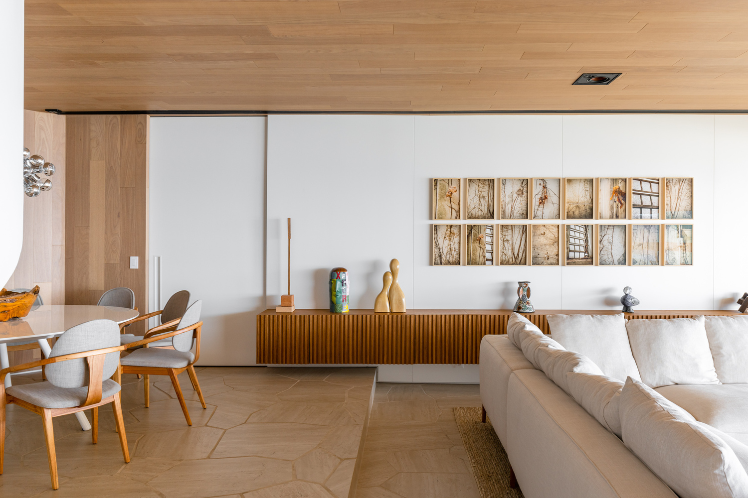 Living room with timber credenza and white walls displaying a grid of framed photographs