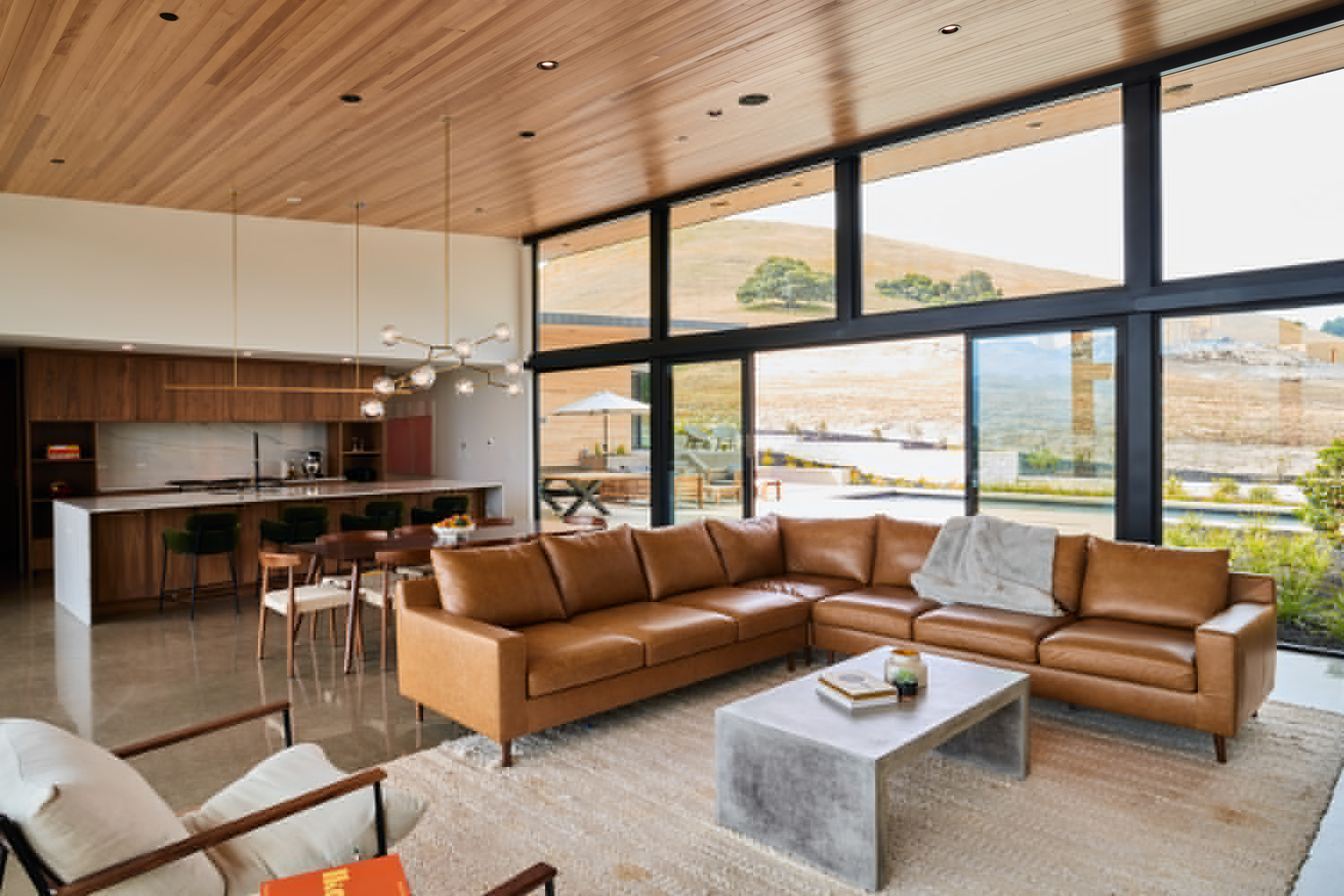 Open living space with timber ceiling and floor-to-ceiling glazing framing distant hillside views