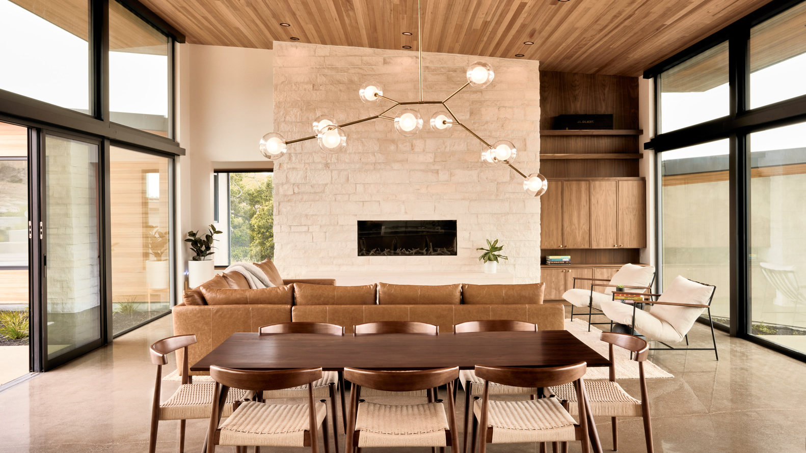 Living and dining space with limestone fireplace wall and clerestory windows under timber ceiling