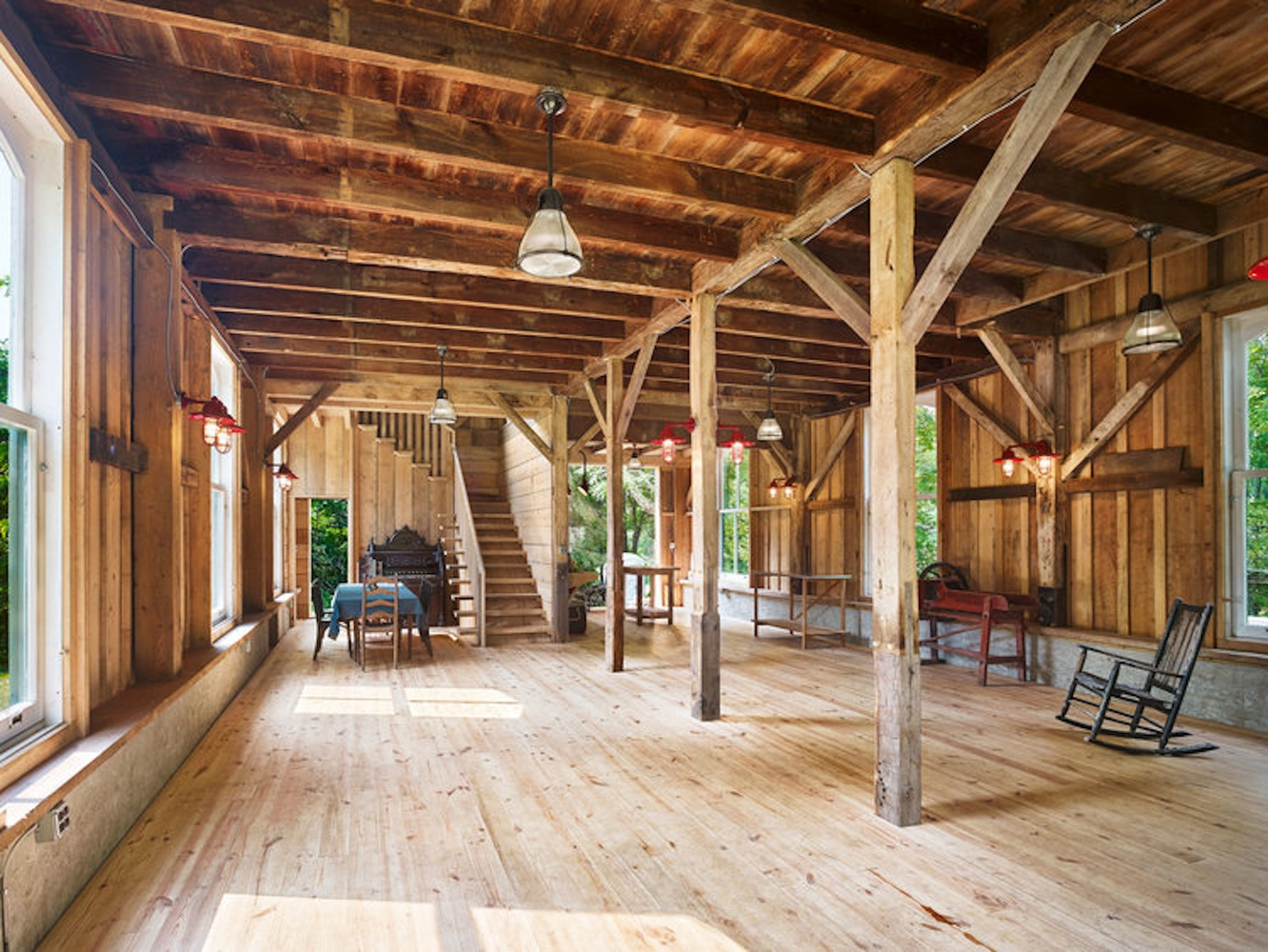 Open-plan interior with exposed timber post-and-beam structure and wide plank flooring in afternoon light