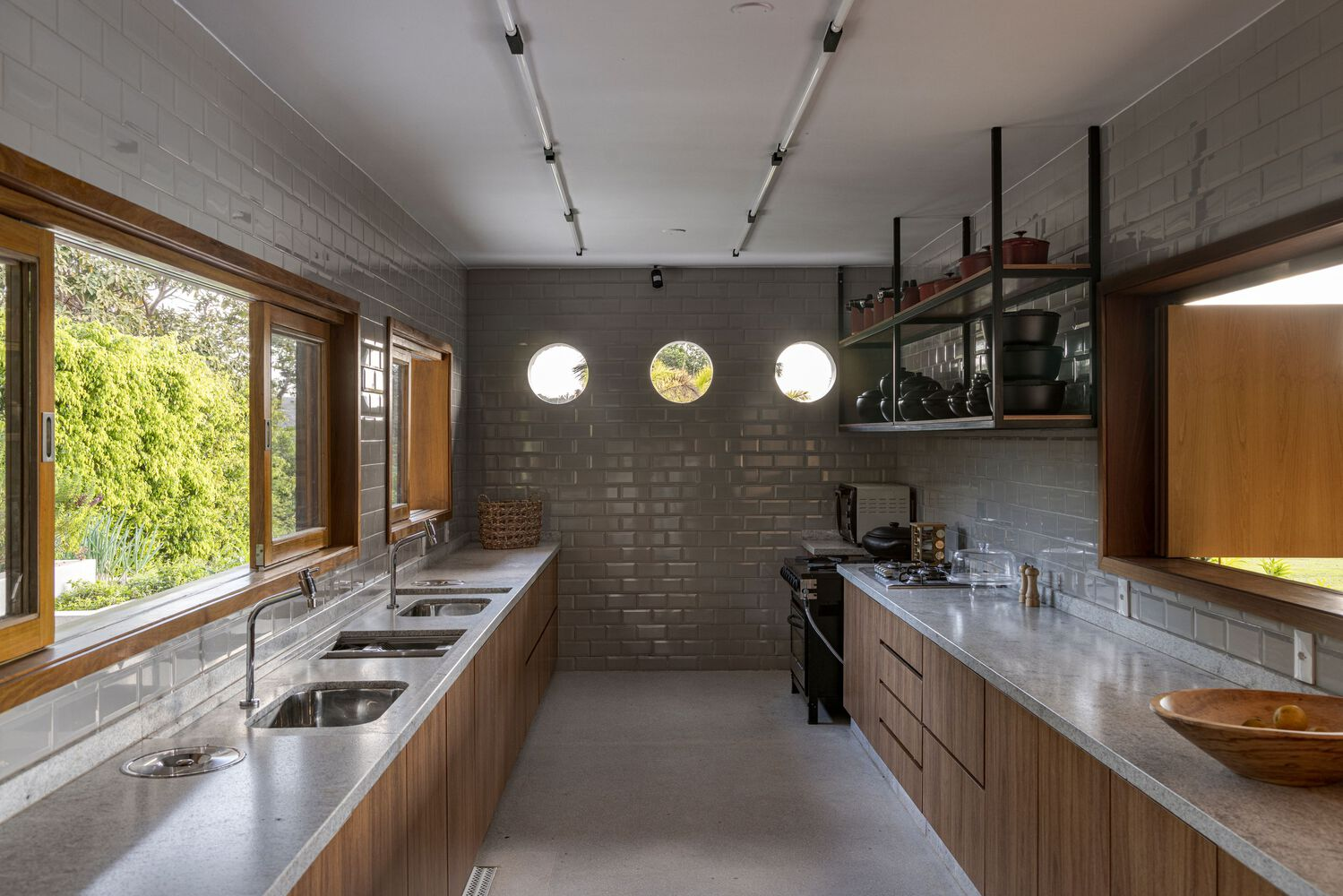 Galley kitchen with concrete block walls, timber cabinetry and three circular windows