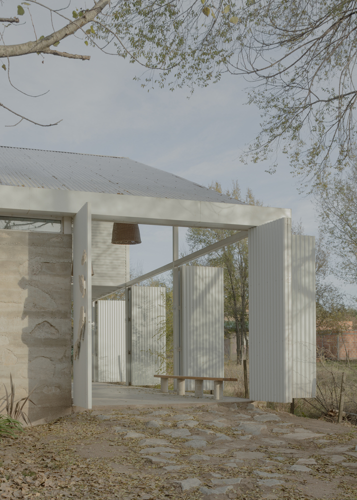 Open passageway framed by white painted timber columns and corrugated metal siding in afternoon light