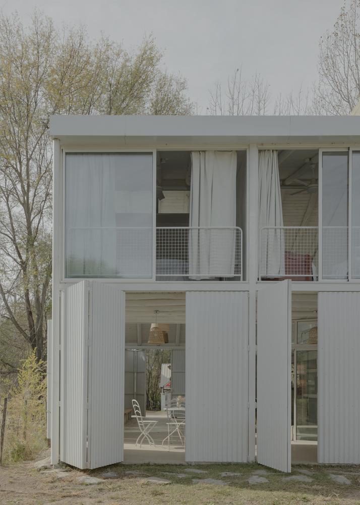Two-story facade with corrugated metal folding panels and ribbon windows framed by bare trees