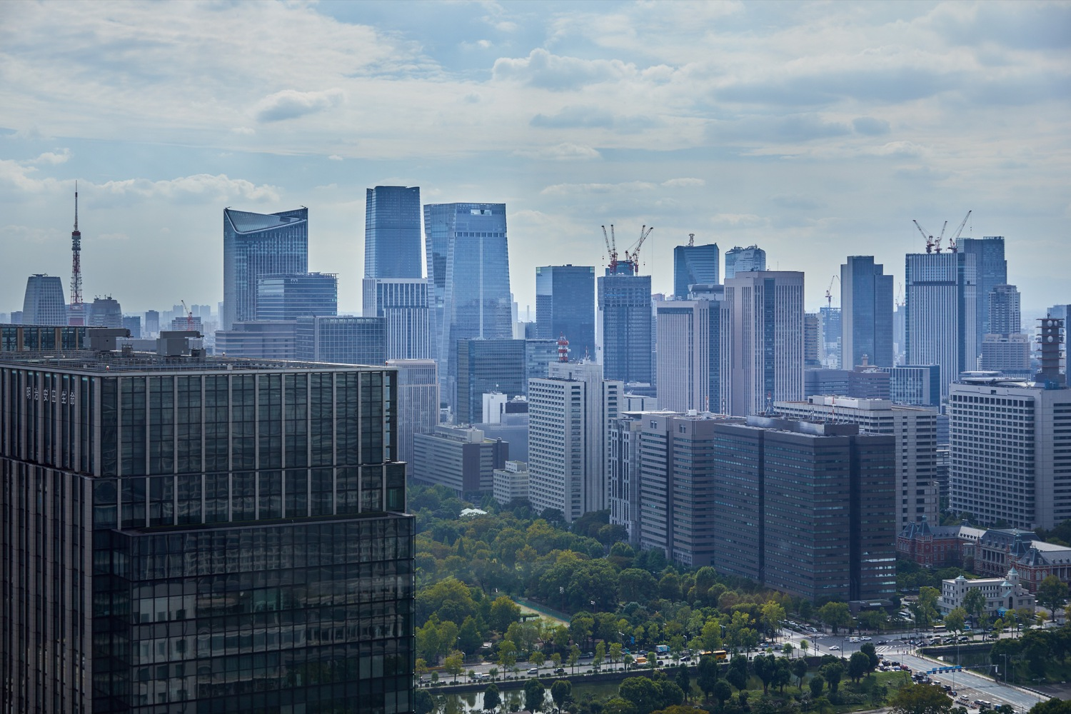 Cityscape showing the stepped glass tower among surrounding high-rises under cloudy skies