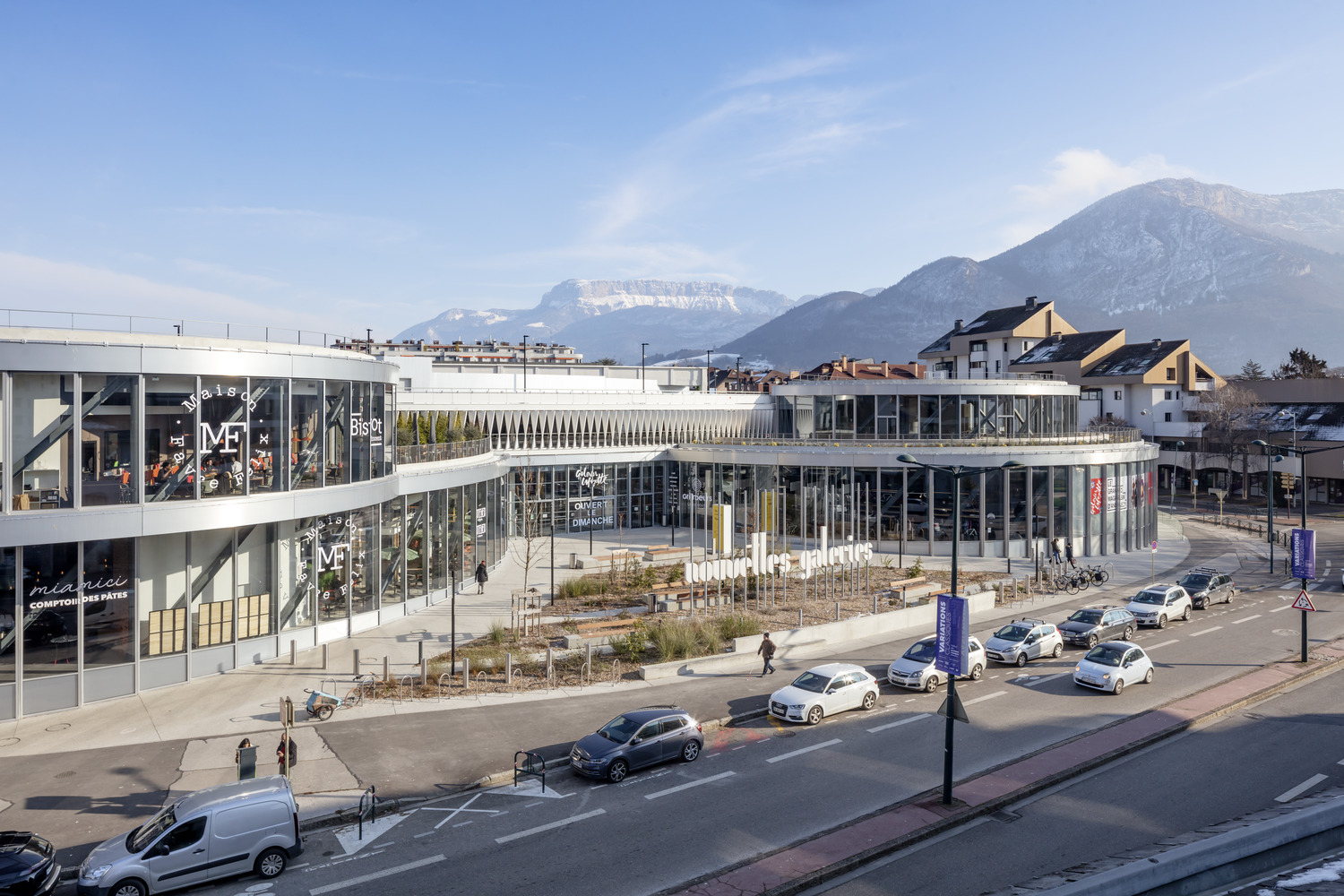 Aerial view of the curved glass and metal complex with mountains rising in the background