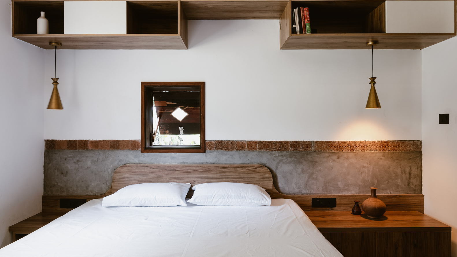 Bedroom with timber headboard wall, concrete wainscoting, and floating shelves with brass pendant lights