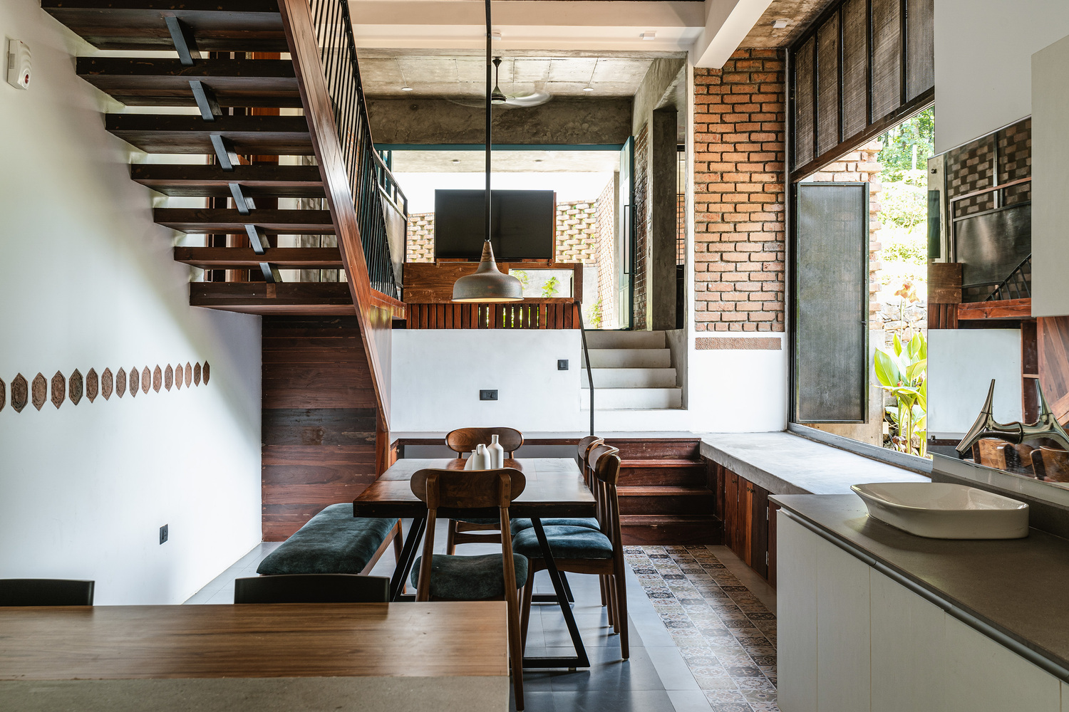 Open-plan kitchen and dining area with timber stair, exposed brick walls, and stepped interior levels