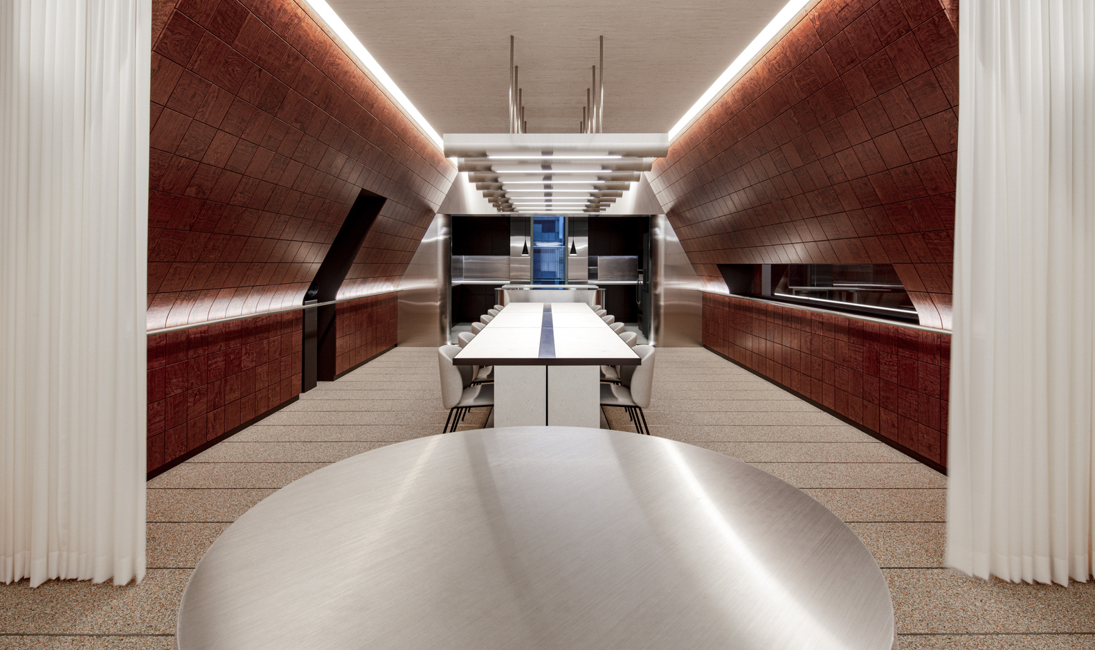 Long dining table with white surface running beneath curved red-tiled walls and suspended ceiling lights