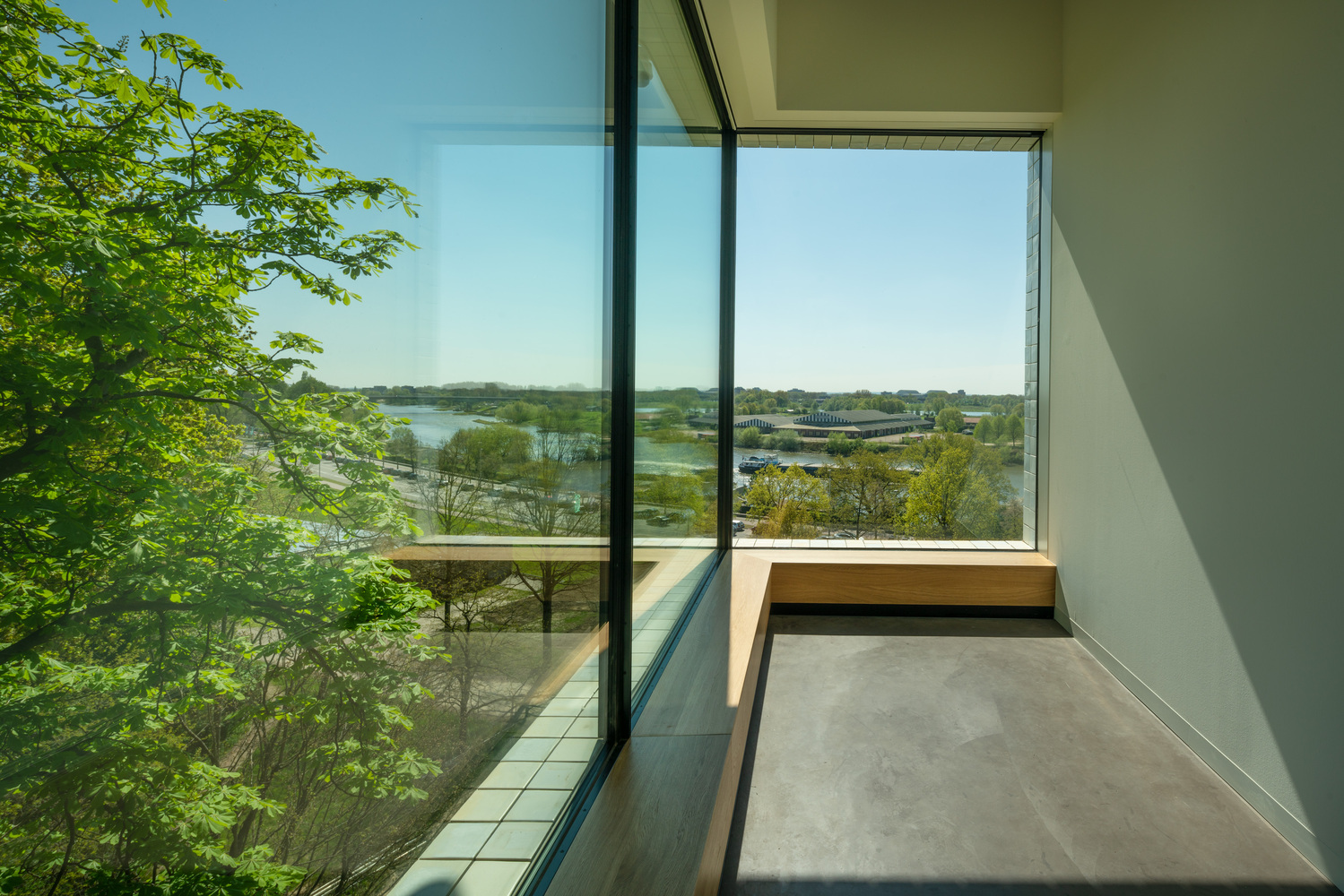 Corner window with built-in bench overlooking the river and wetlands beyond green foliage