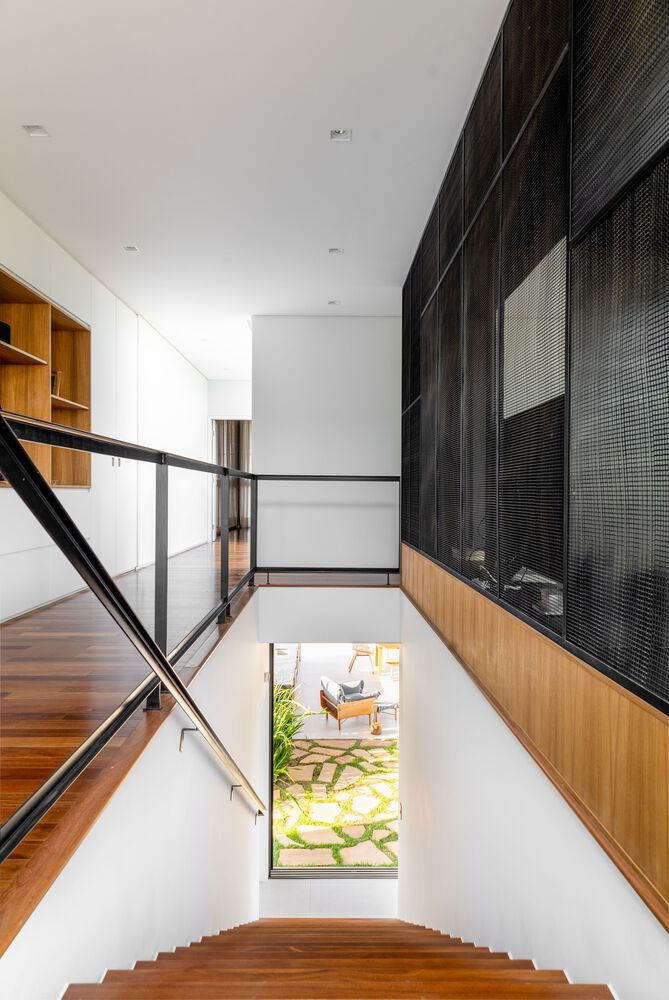 Interior stairwell with timber treads descending alongside a wood and metal mesh wall panel