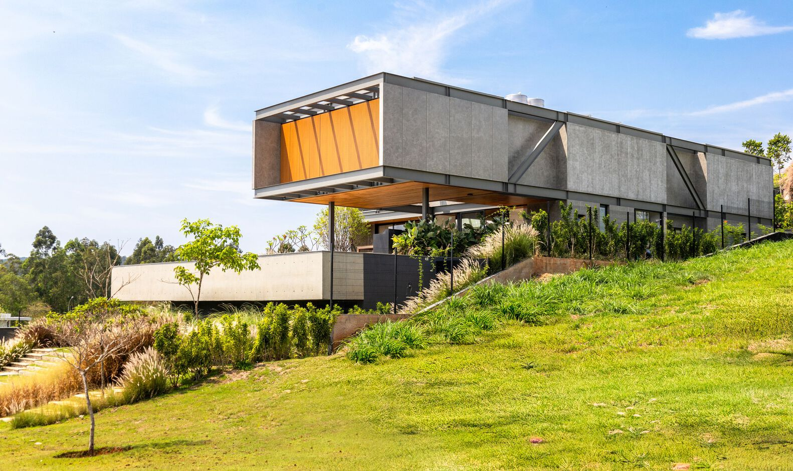 Side view of the cantilevered volumes on a sloping lawn with timber screens and concrete walls