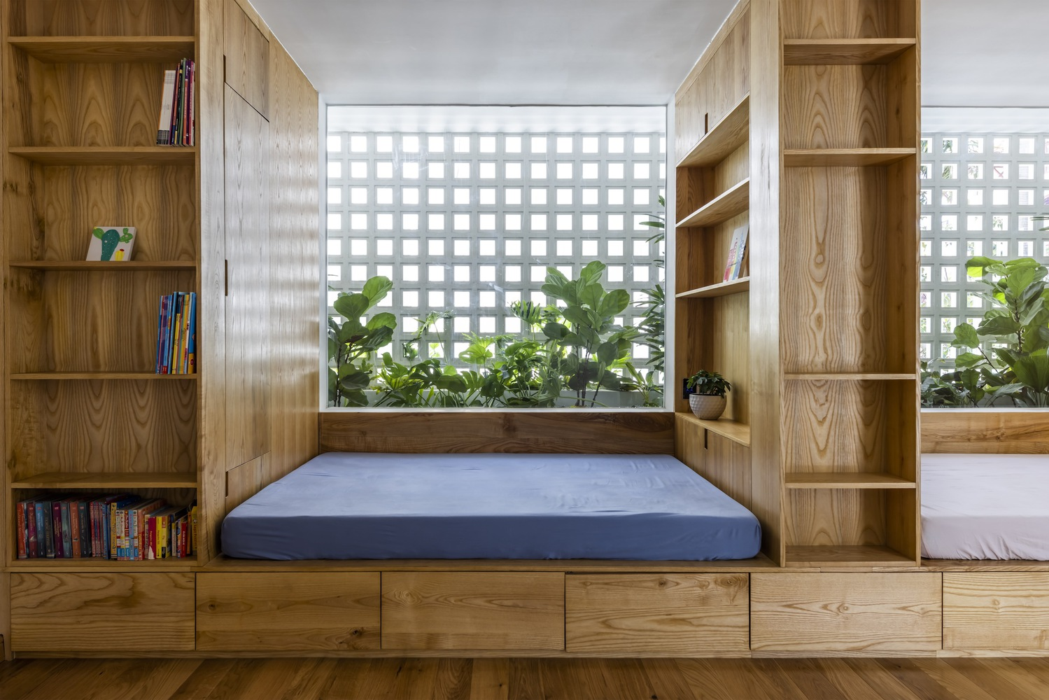 Built-in timber sleeping alcoves with shelving and gridded screens filtering daylight and greenery