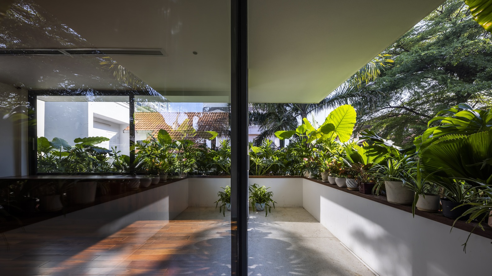 Sliding glass doors opening to a planted balcony with banana palms and dappled morning light