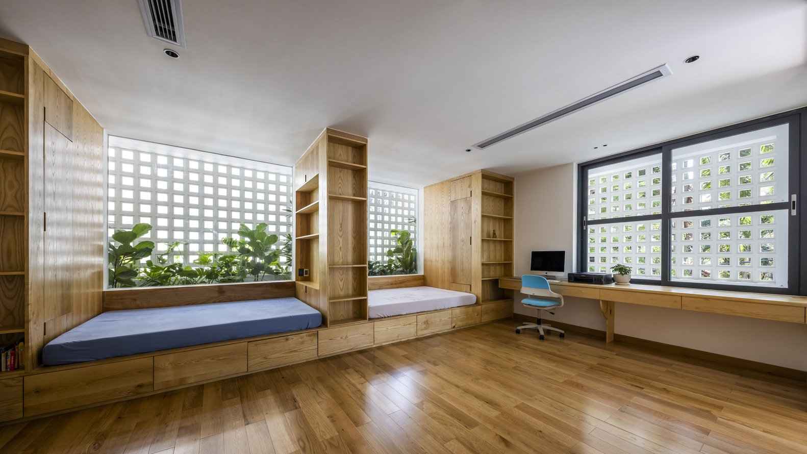 Multipurpose room with timber nooks, built-in desk and perforated block windows admitting filtered daylight