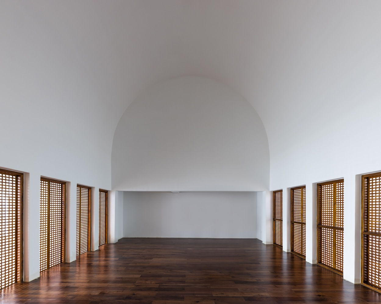 Barrel-vaulted interior with timber lattice doors lining the curved walls above dark wood flooring