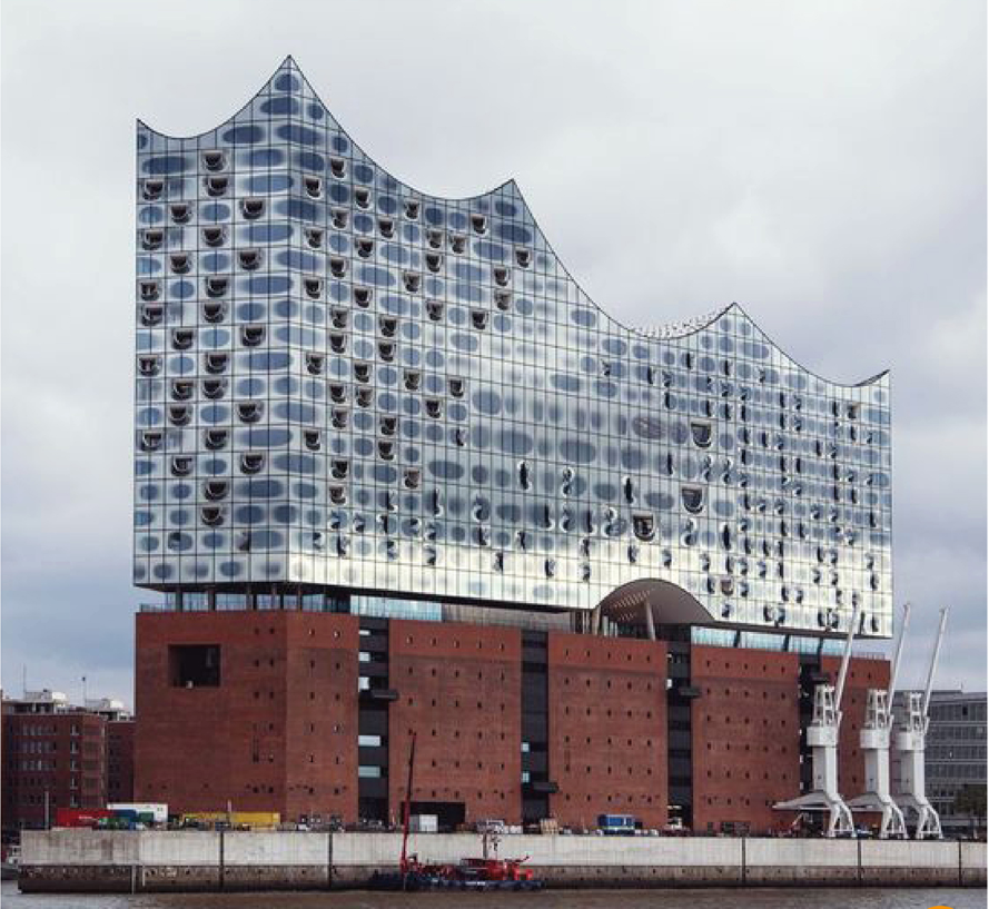 Waterfront facade with wave-shaped glass curtain wall rising above a red brick podium under overcast sky