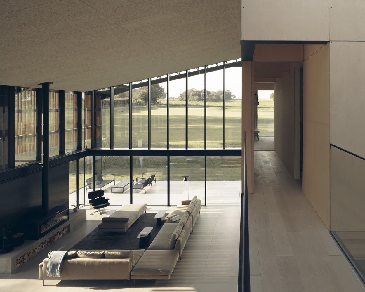 Double-height living room with floor-to-ceiling glazing overlooking an open lawn