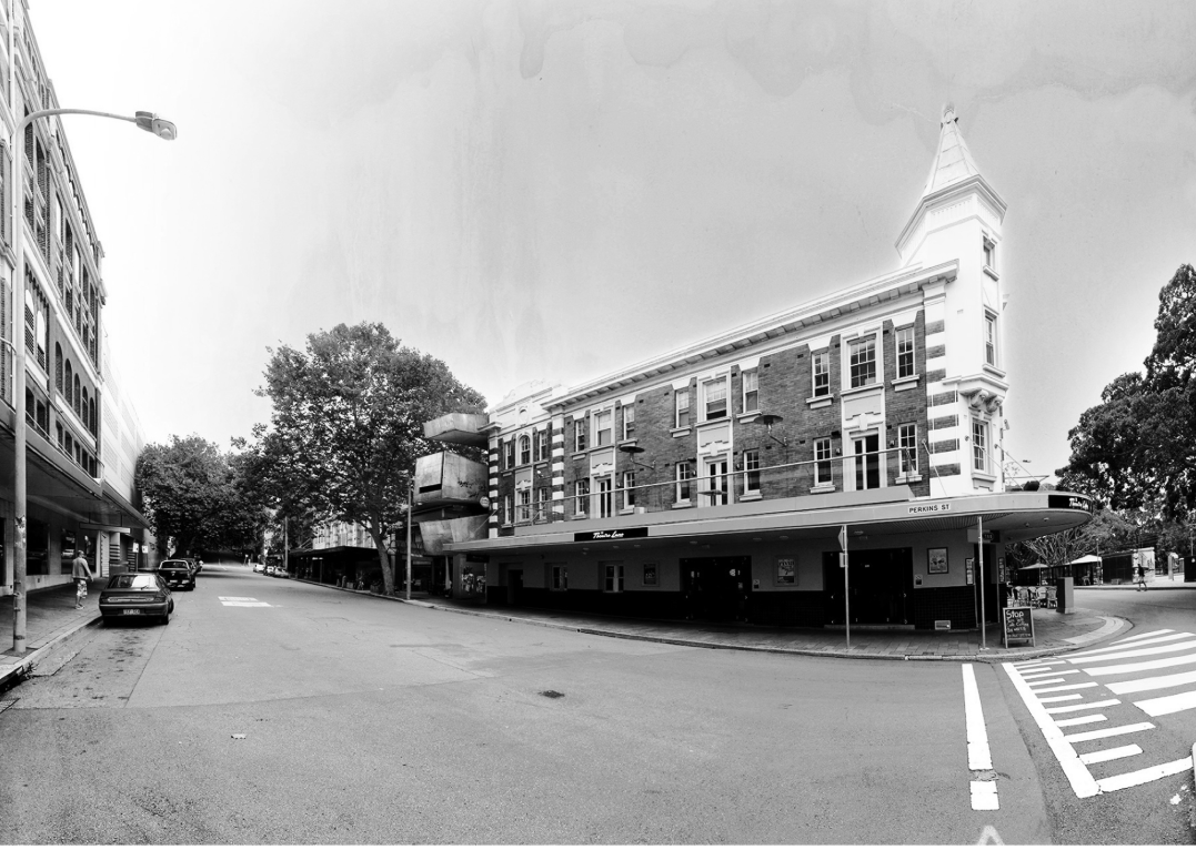 Street corner view of a brick building with a corner tower and covered ground-level awning
