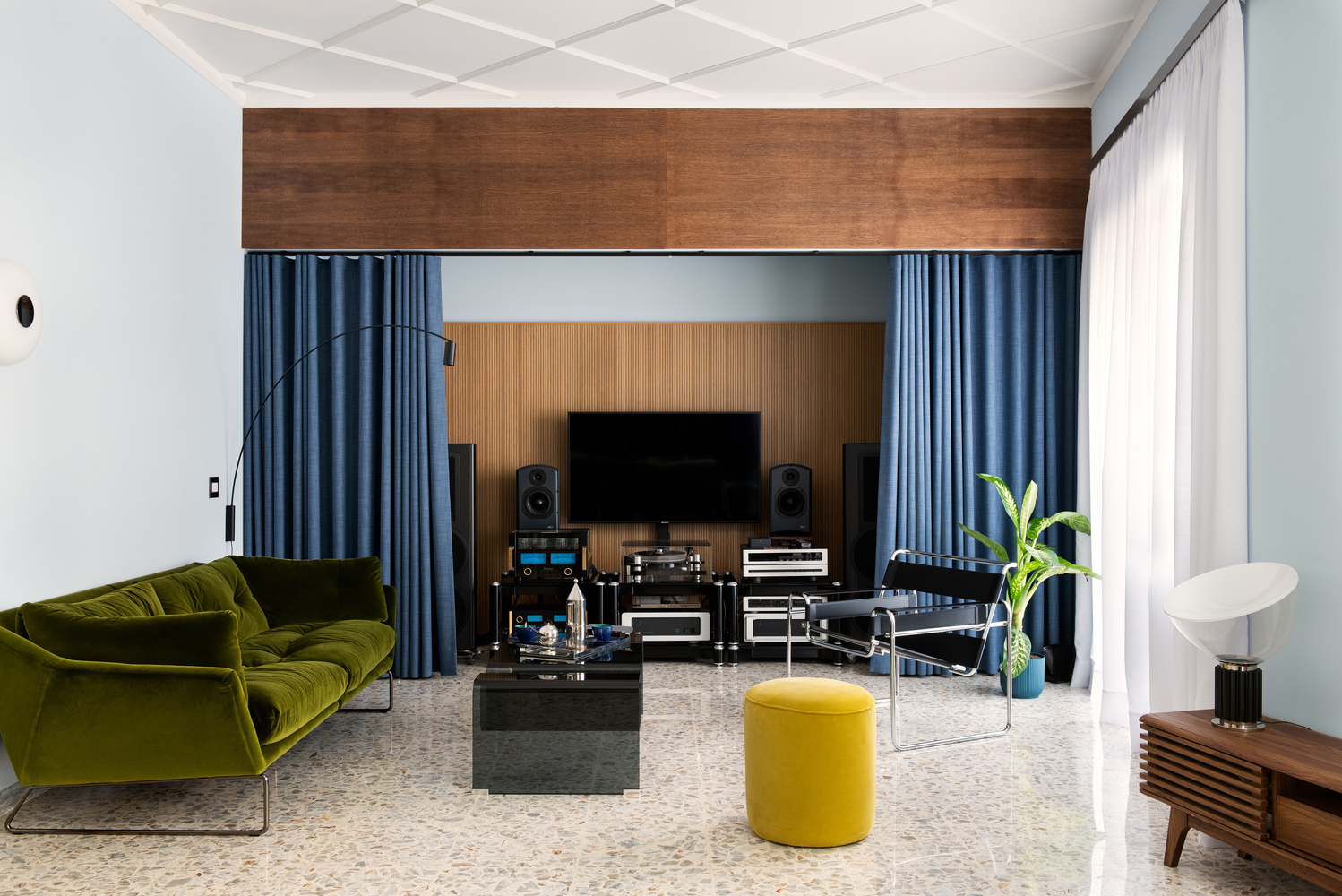 Living room with terrazzo flooring, coffered ceiling, and timber-framed media wall with blue curtains
