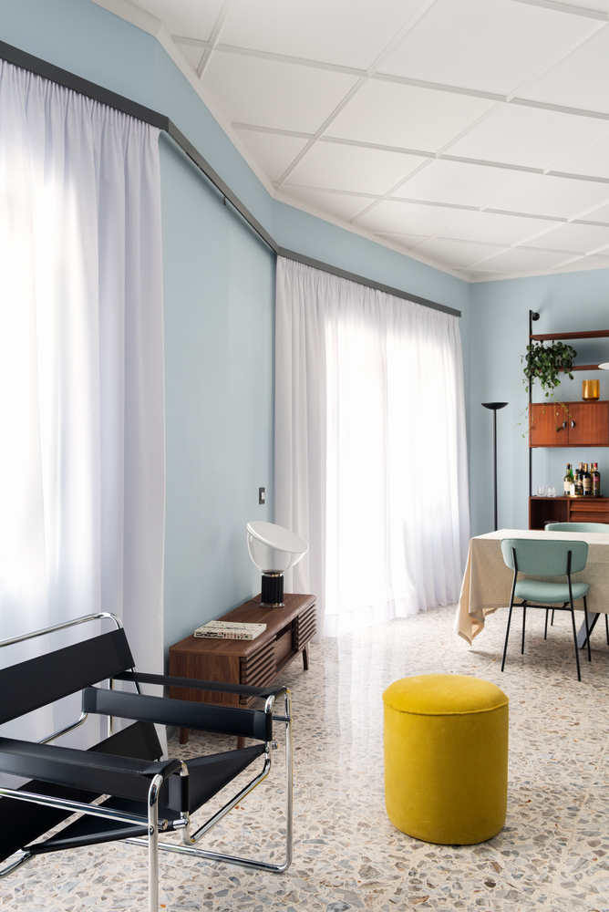 Open living area with curved pale blue walls, white coffered ceiling and terrazzo flooring