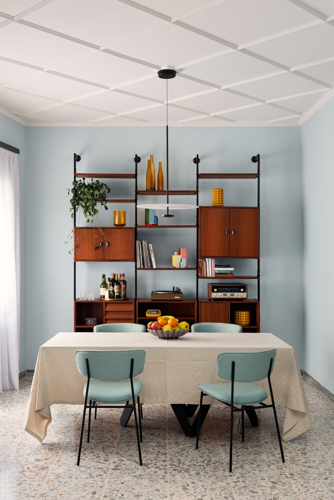 Wall-mounted modular shelving unit with timber cabinets and black metal framework above a dining table