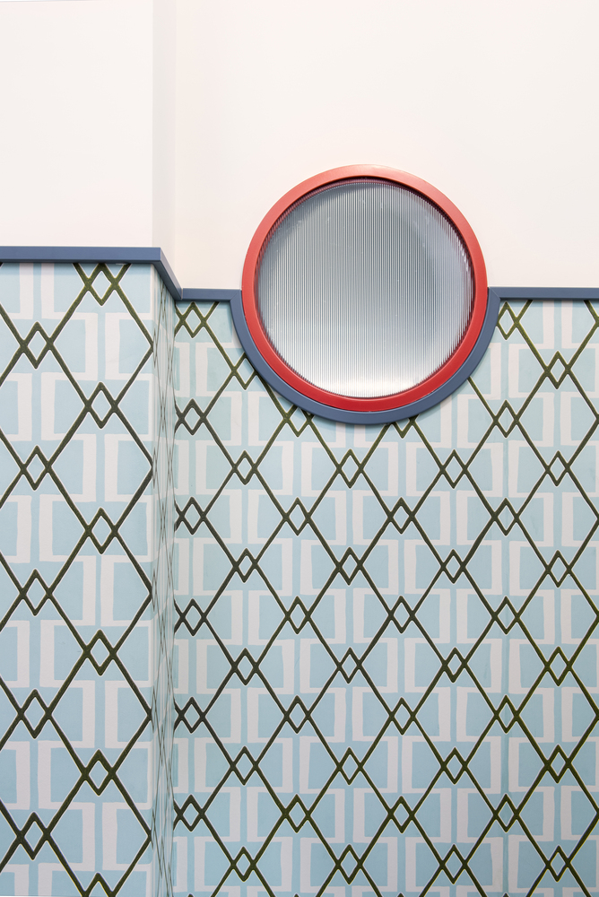 Patterned tile wall with blue border trim, round window and diagonal lattice motif