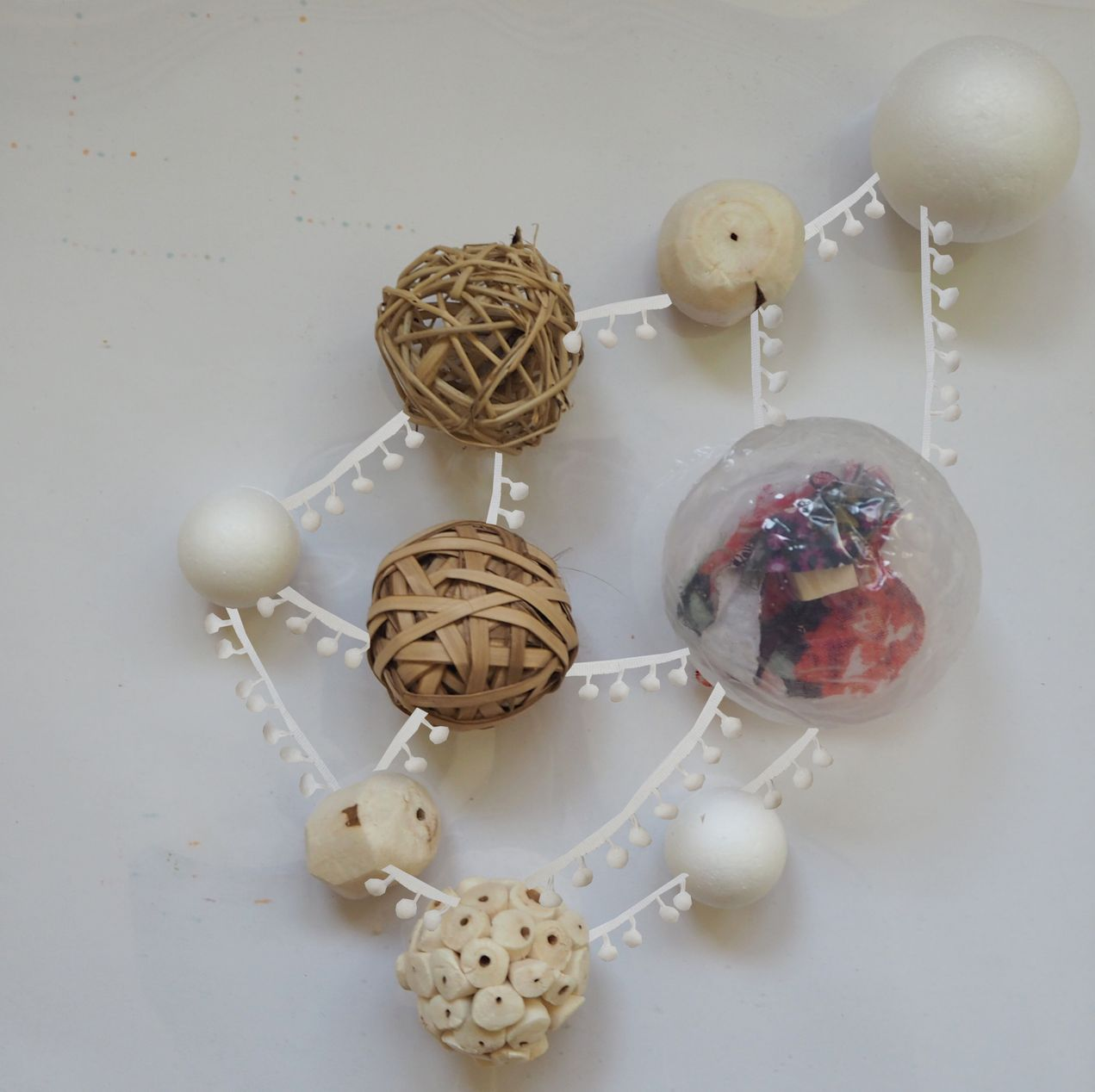 Top-down view of a study model with woven spheres and white structural frames on a white surface