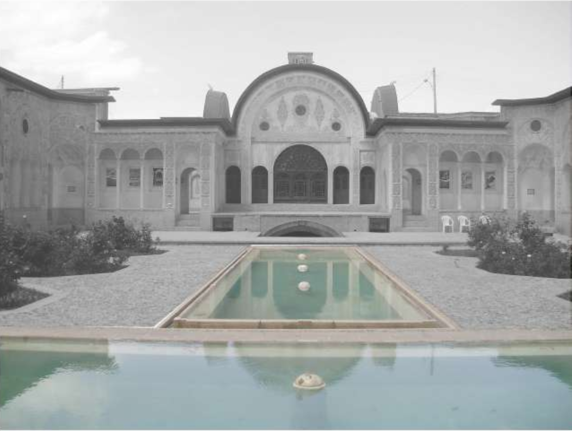 Symmetrical courtyard facade with central arched portal and turquoise reflecting pools framed by planted beds