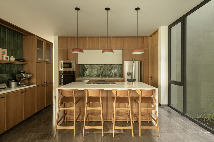 Kitchen with timber cabinetry, central island with bar seating and three pendant lights overhead