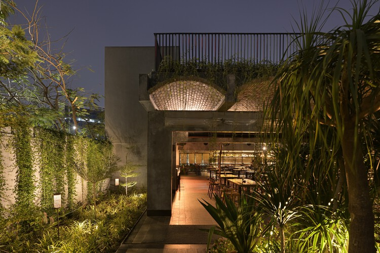 Entrance pathway at dusk with uplighting through planted beds and woven basket lights hanging above the doorway