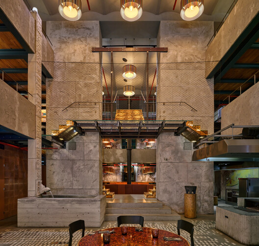Double-height lobby interior with exposed concrete walls, geometric lighting fixtures, and mezzanine walkways
