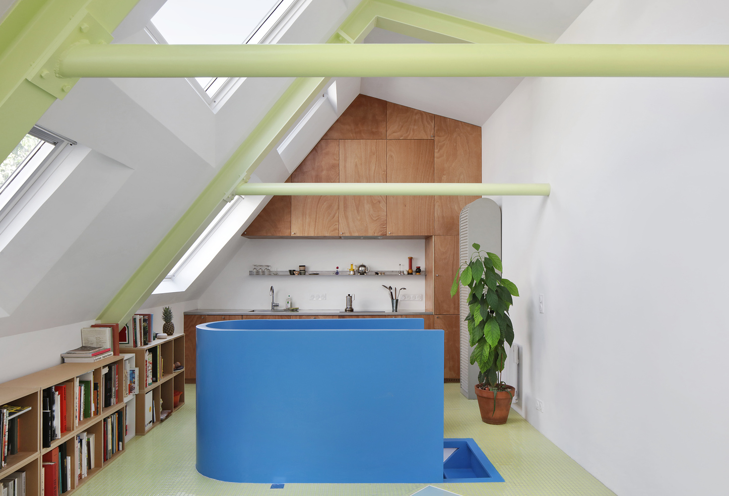 Attic kitchen with blue laminate island under lime green exposed beams and sloped skylights