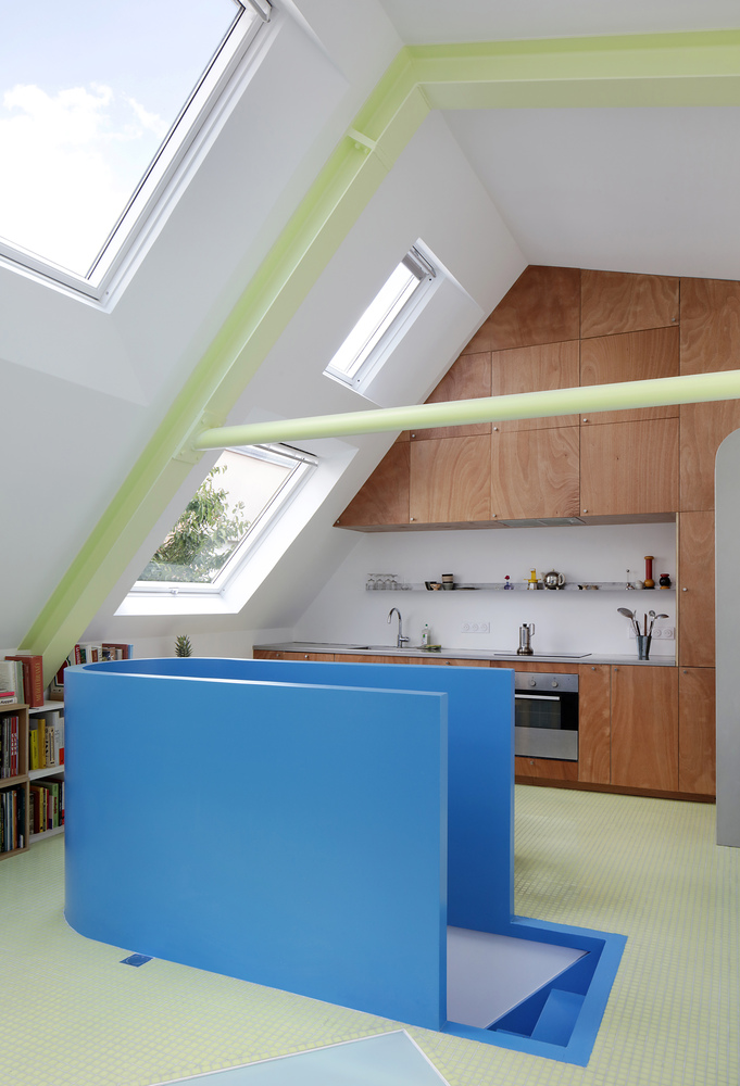 Blue stepped island with wood veneer cabinetry in an attic space with skylights framing trees