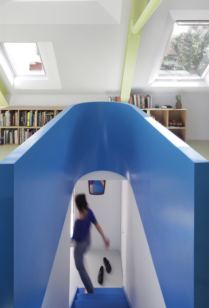 Arched blue partition with a figure in motion descending the integrated stairway beneath