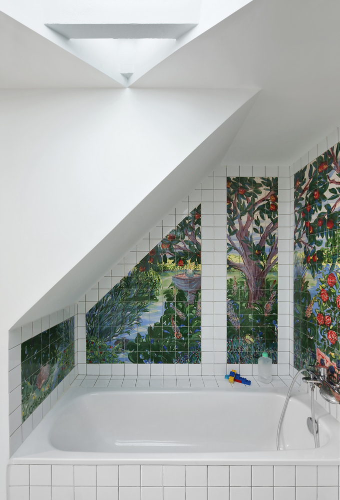 White tiled bathroom niche with tropical painted mural and a skylight above the tub