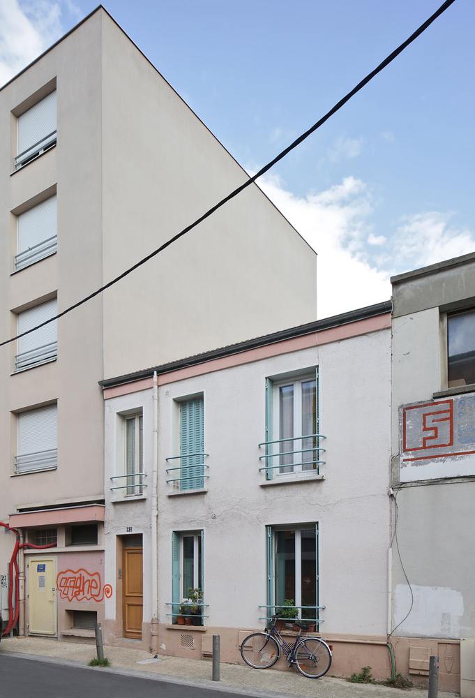 Urban street facade showing a renovated white rowhouse with balconies beside older neighboring buildings