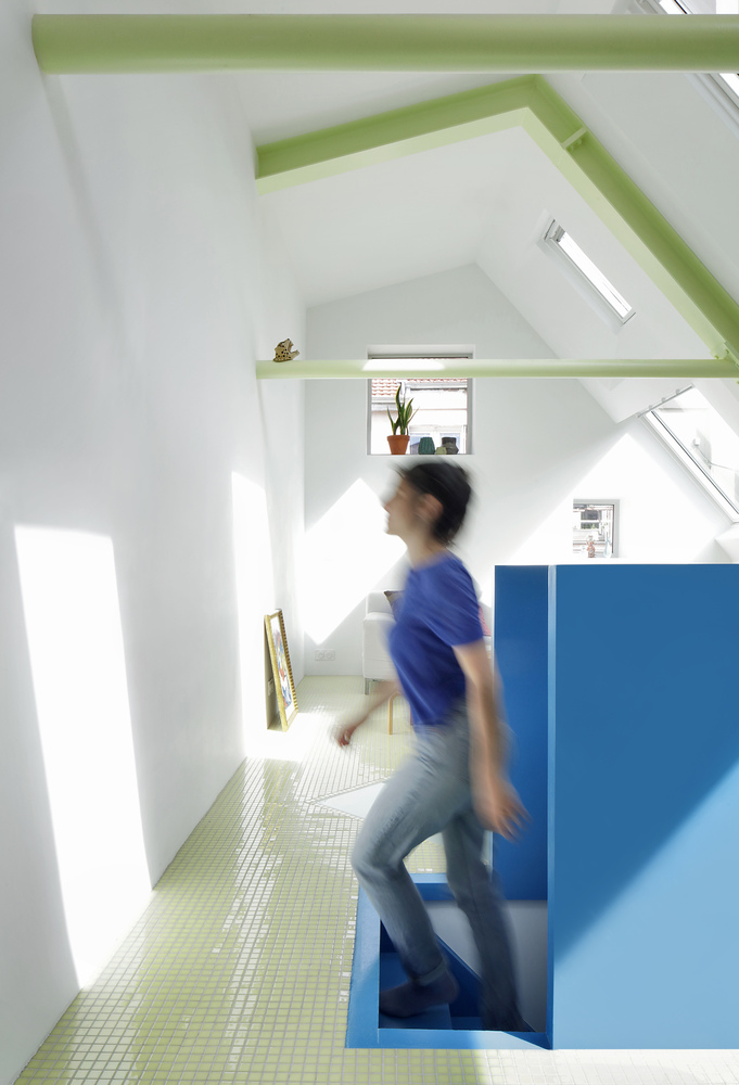 Split-level interior with blue stair volume and skylights flooding white walls with natural light