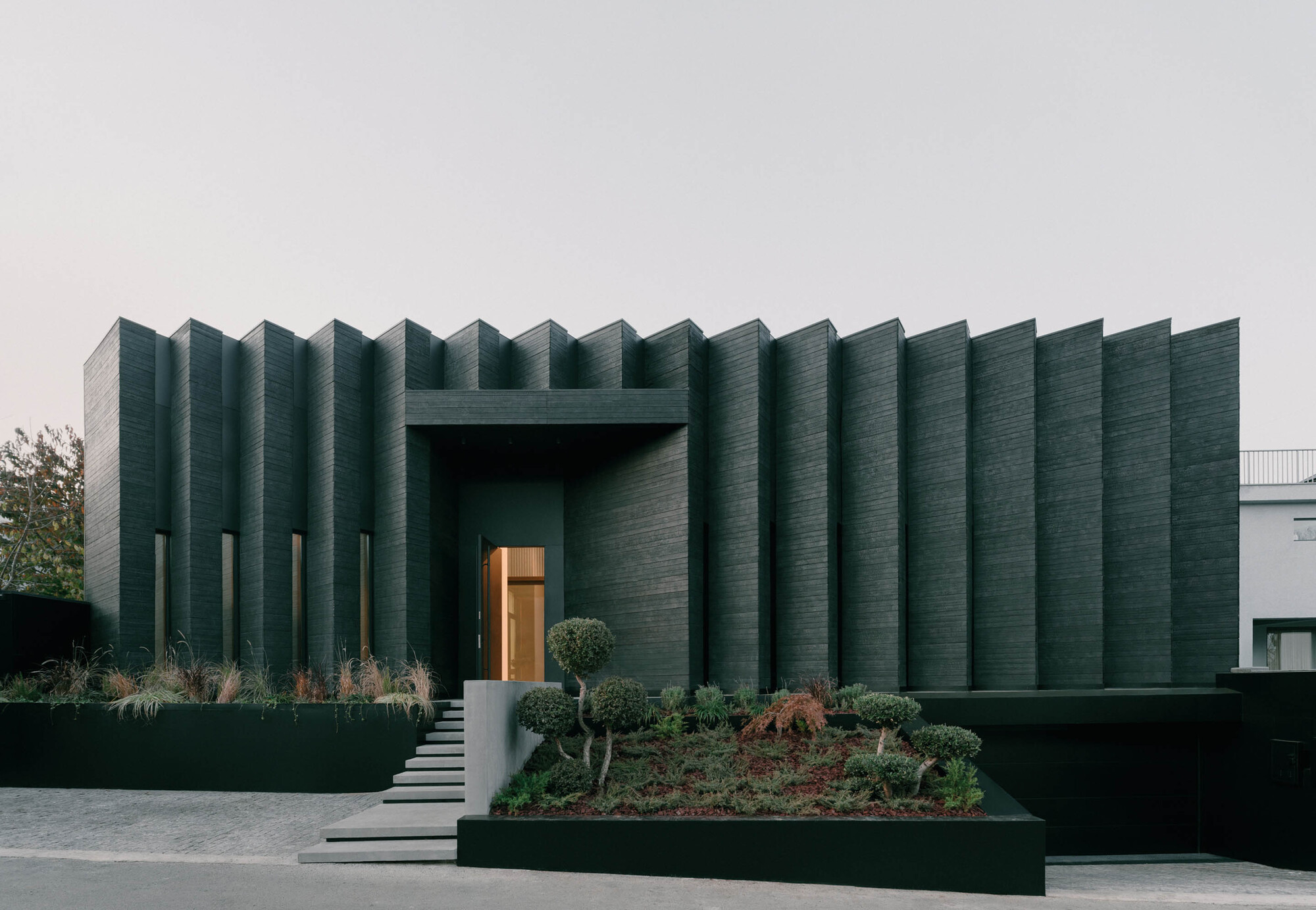 Ribbed facade with vertical fins and recessed entry under overcast sky