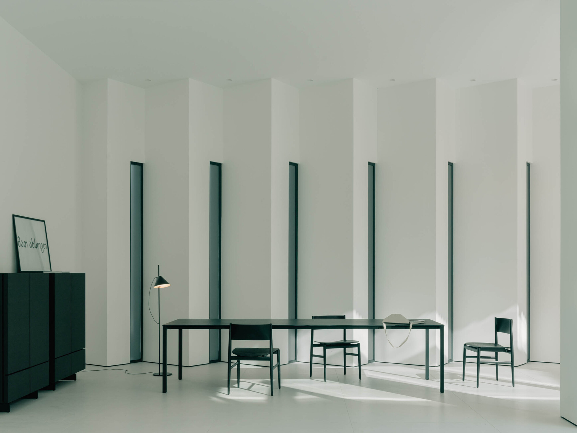 Dining room with rhythmic vertical window slots framing dark green table and chairs