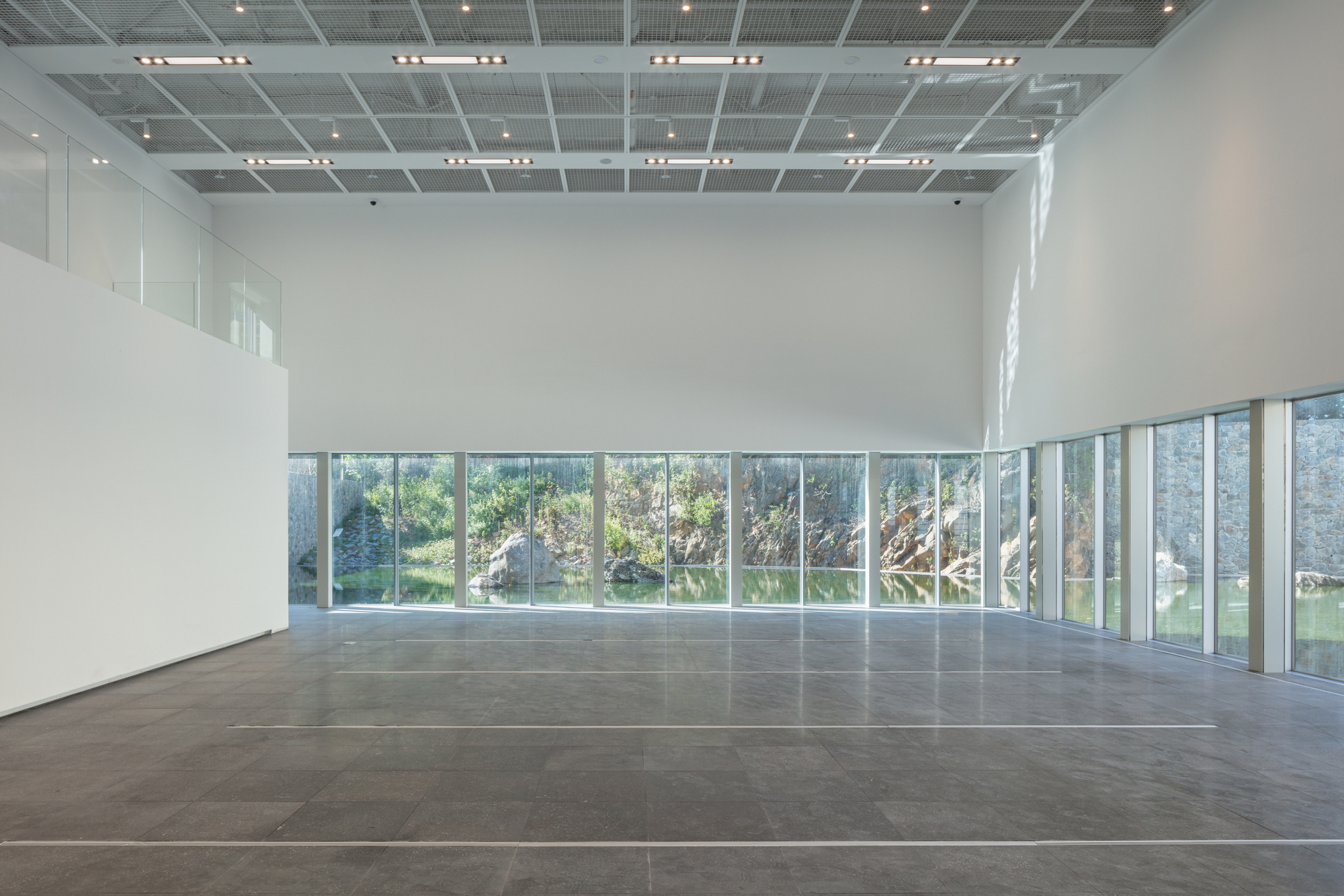 Corner gallery with full-height windows framing views of an outdoor courtyard and vegetation