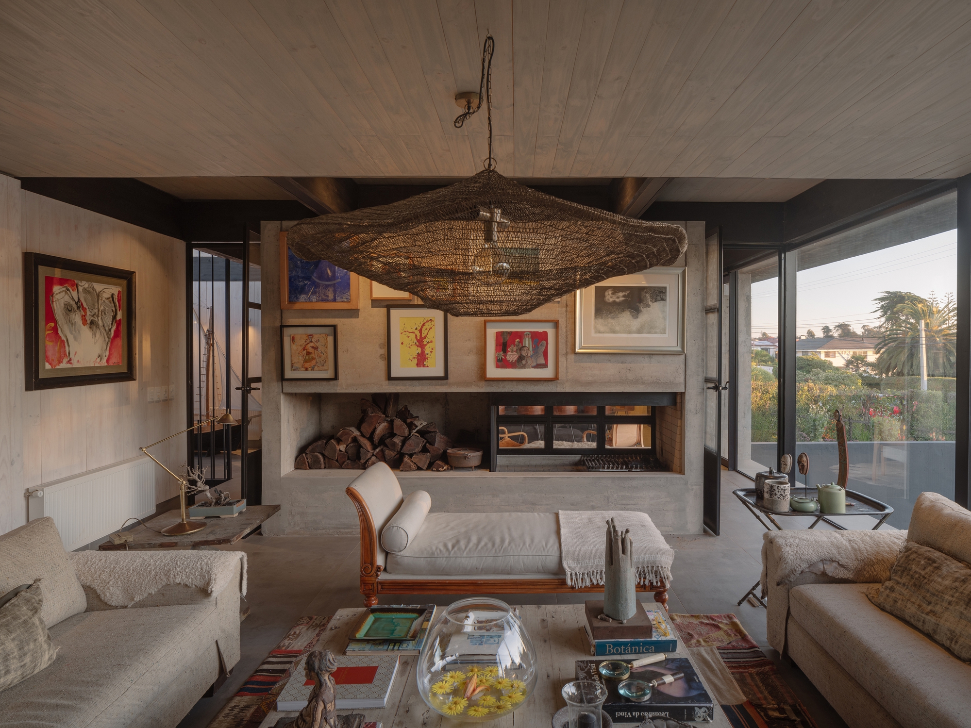 Living room with concrete fireplace surround and timber plank ceiling beneath a large woven pendant light