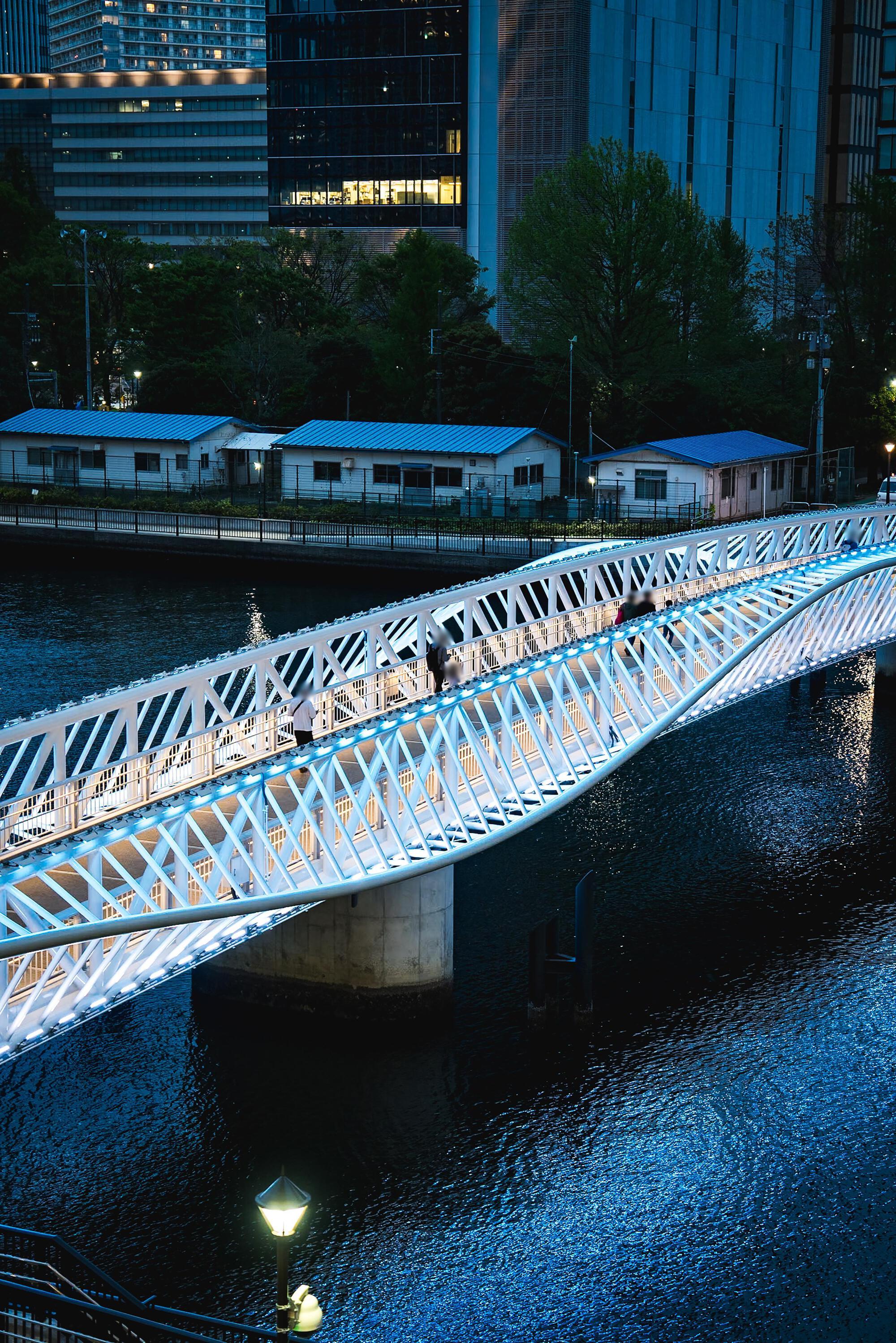 Angled view of the latticed bridge deck with pedestrians crossing at twilight