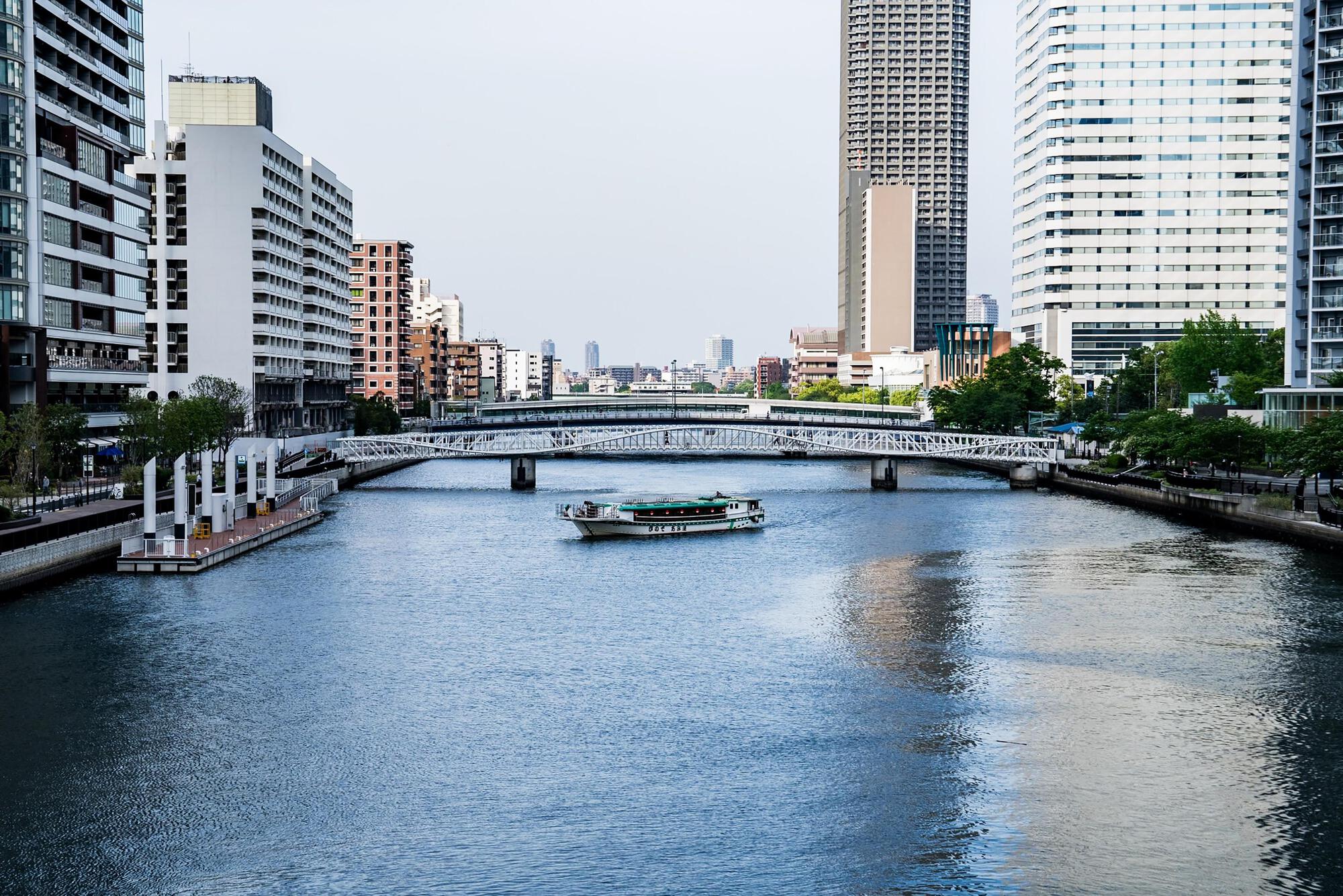 Long view of the white lattice bridge crossing the canal with a ferry boat underneath