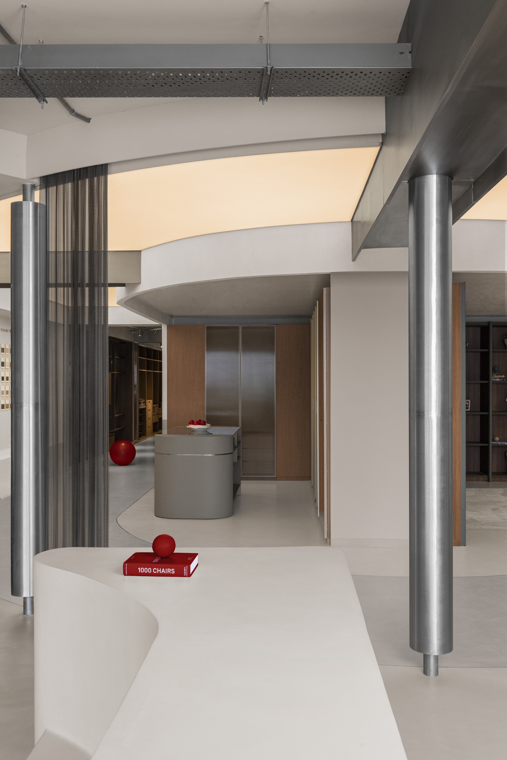 Curving white display counter with metal columns and overhead beams in a retail space