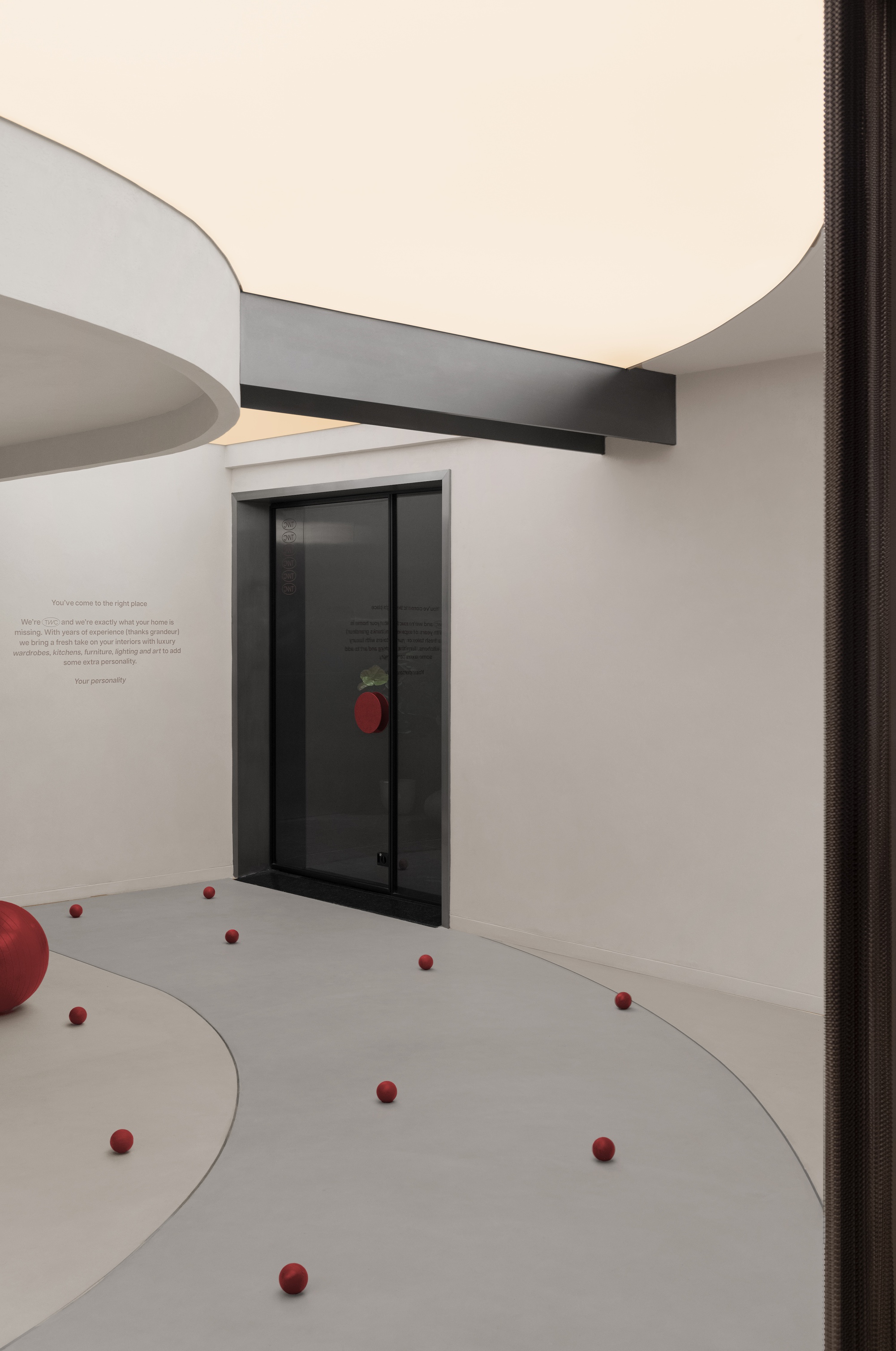 Corner view of a glazed door with red spheres arranged across the pale floor